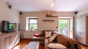 A living room with a sofa, a coffee table, a TV, a window, and a radiator. - Stunning  villa for 5 people with WIFI, TV, patio and pets allowed (Chez Croiset)