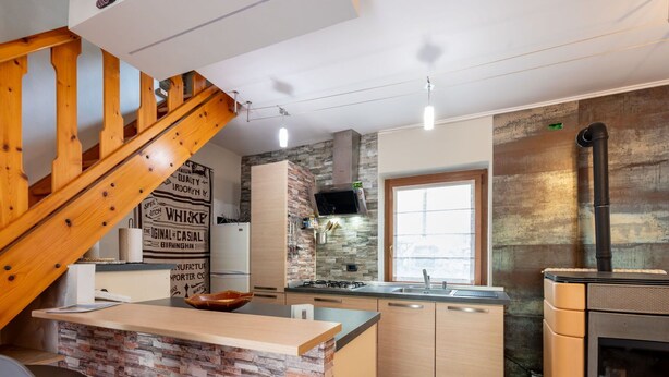A modern kitchen with a stone backsplash, wooden cabinets, a built-in island, and a wood-burning stove. - Stunning  villa for 5 people with WIFI, TV, patio and pets allowed (Chez Croiset)