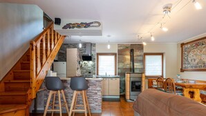 A cozy interior with a wooden staircase, a kitchen with a stone backsplash, a dining area with a large map, and a living room with a sofa. - Stunning  villa for 5 people with WIFI, TV, patio and pets allowed (Chez Croiset)