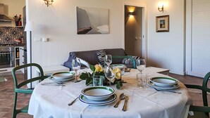 A dining area with a round table set for four, surrounded by green chairs. There is a sofa against the wall, a painting above the sofa, and a door leading to another room. - Beautiful private villa for 6 people with private pool, A/C, WIFI, TV, terrace and pets allowed (Monreale)