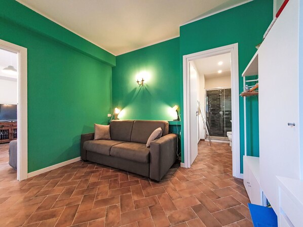 A living room with a green wall, a brown sofa, and a tiled floor.