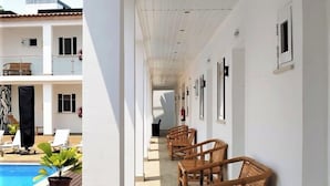A corridor with wooden benches and a pool area visible to the left.