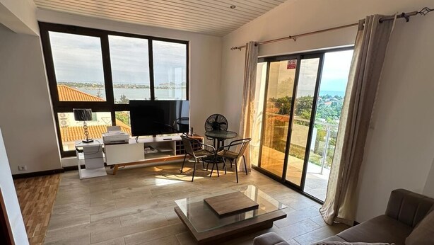 A modern living room with a large window, a sofa, a coffee table, and a TV.