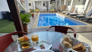 A breakfast setting with a plate of toast, ham, and eggs, a glass of orange juice, and a small dish of fruit.