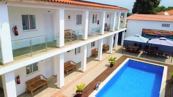 A two-story building with a swimming pool, outdoor seating, and a mural on the exterior wall.