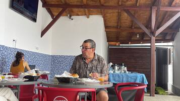 Un restaurante con vigas de madera en el techo, un televisor montado en la pared y sillas rojas y negras.