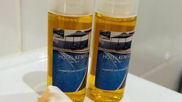 Two bottles of Hotel Kenito shampoo and shower gel on a white surface.