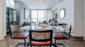 Un espace repas moderne avec une table en verre, des chaises en métal et un luminaire suspendu au plafond.