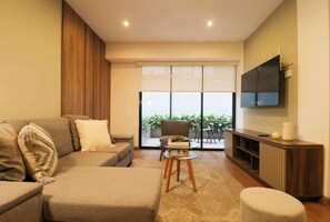 A modern living room with a sofa, ottoman, and a glass coffee table.