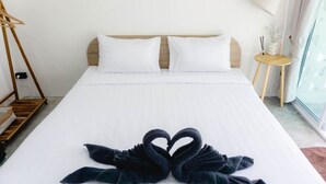 Ein Hotelzimmer mit einem ordentlich bezogenen Bett, einem Nachttisch mit Lampe und einem Fenster mit Vorhängen.