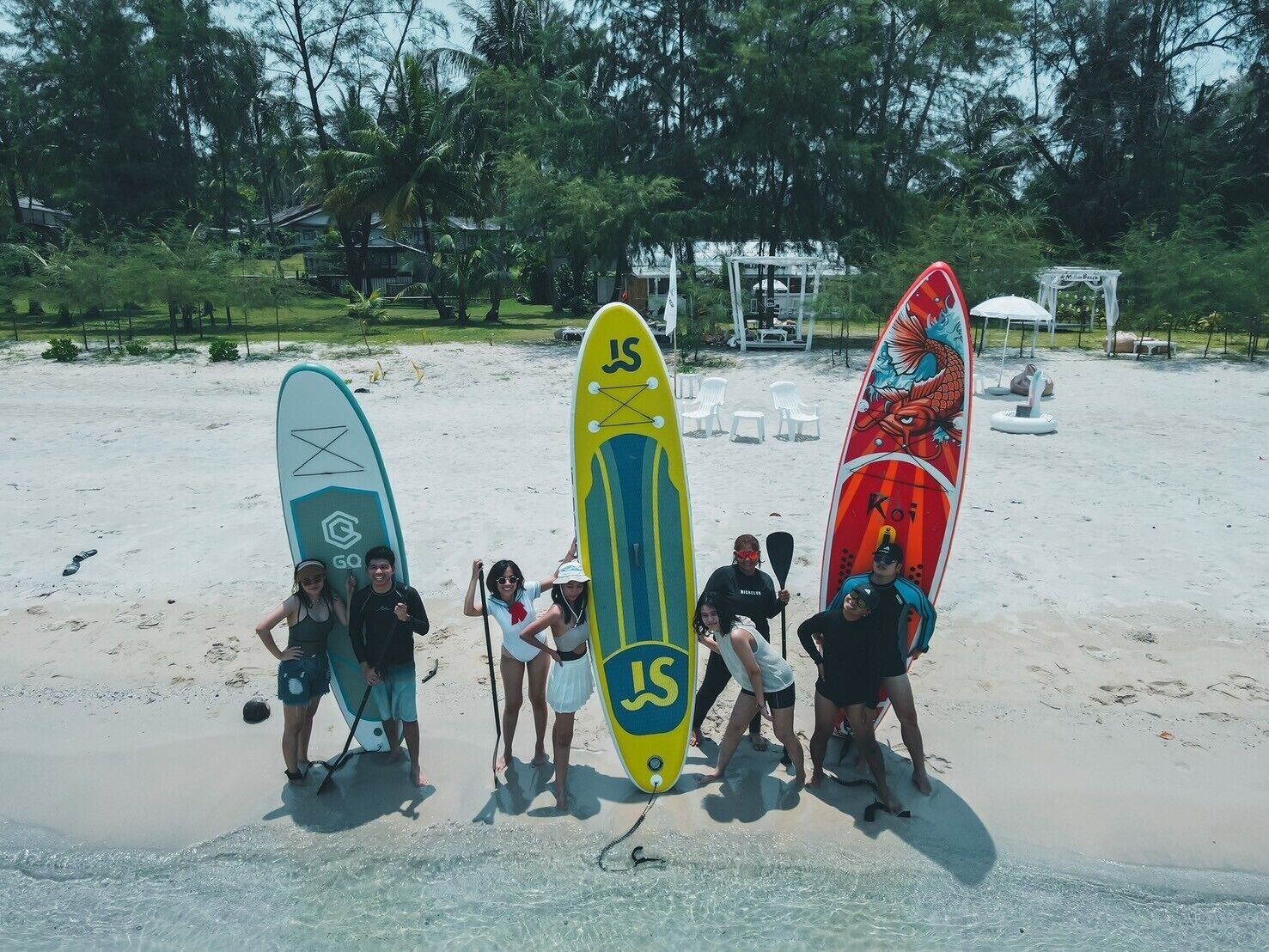 Un grupo de personas de pie en una playa arenosa con tablas de surf.