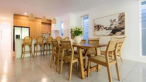 A modern kitchen with wooden cabinets, a dining area with a table and chairs, and a ceiling fan.
