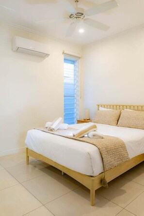 Ein Schlafzimmer mit einem Bett, einem Nachttisch und einem Deckenventilator.