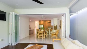 A modern living room with a sofa, a wooden tray, and a dining area with a table and chairs.