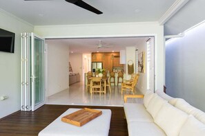 A modern living room with a sofa, a wooden tray, and a dining area with a table and chairs.