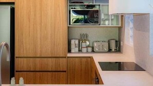 A modern kitchen with wooden cabinets, a built-in microwave, and a hanging light fixture.