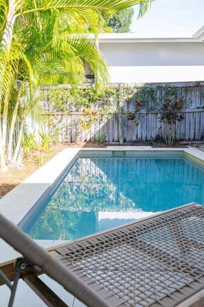 A swimming pool with a wooden deck and a chair.