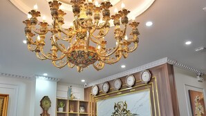 Un candelabro con múltiples brazos y luces, un reloj montado en la pared, y un letrero que dice "Kim Chi An Hotel".