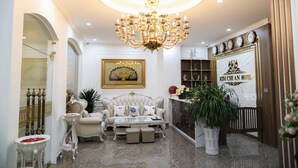 Un lobby lujoso con una imponente lámpara de cristal, muebles elegantes y una recepción.