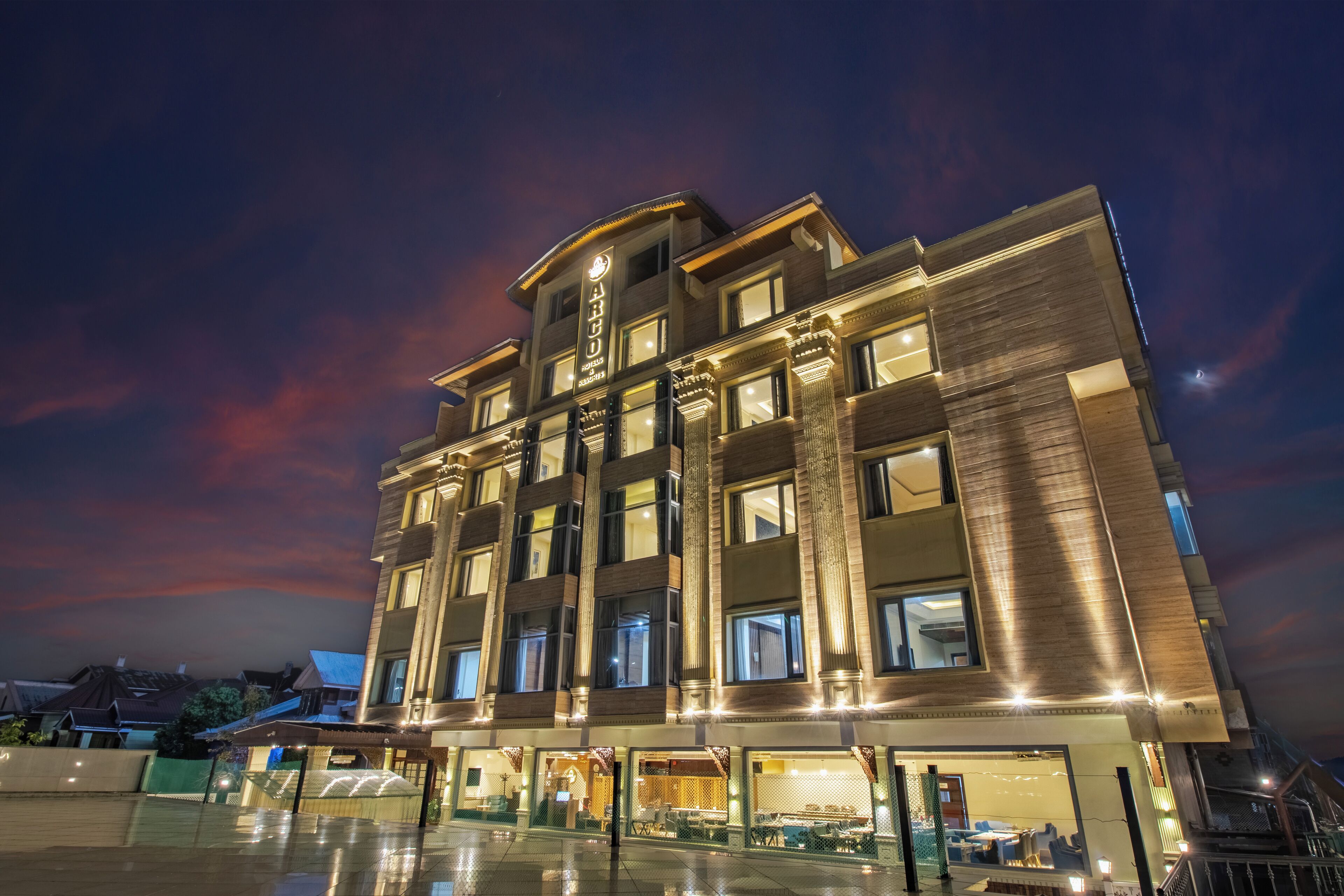 A multi-story hotel with a modern facade, large windows, and a well-lit entrance area.