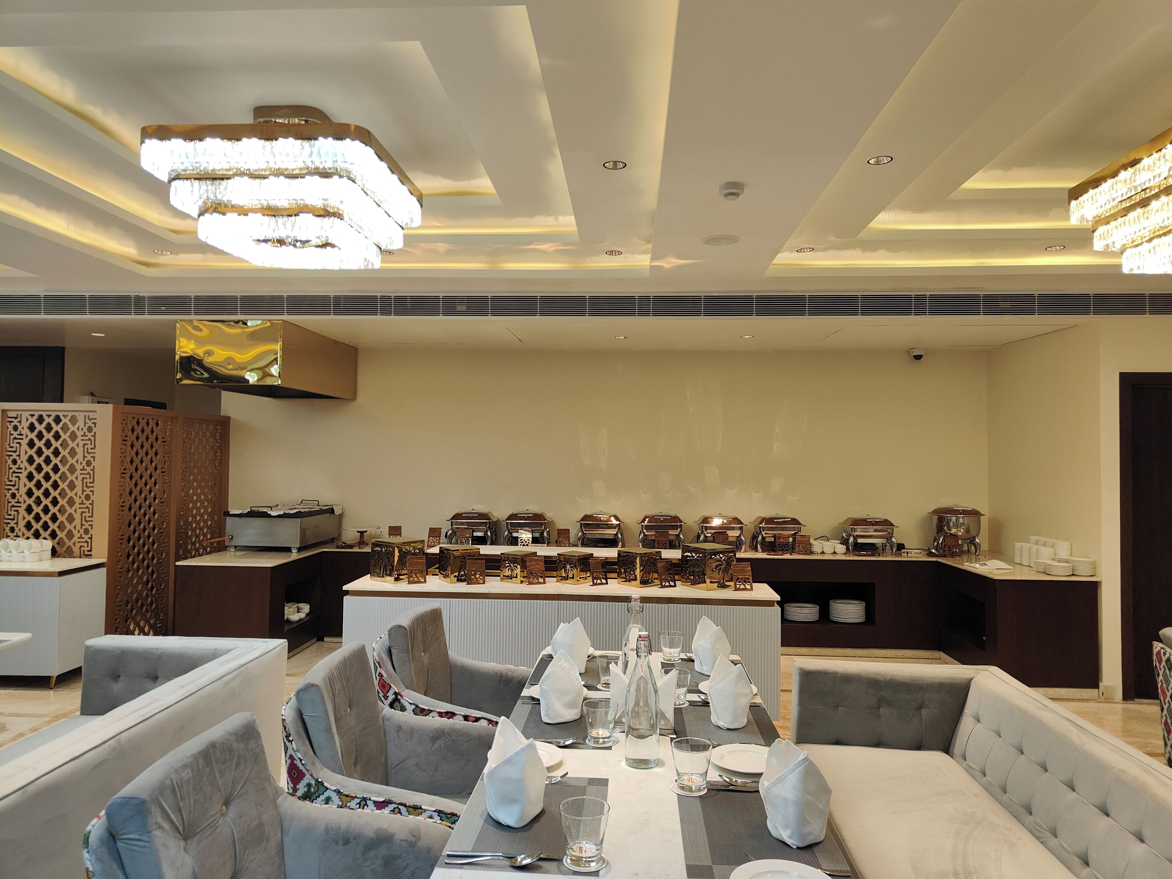 Un comedor bien iluminado con candelabros modernos, mesas ordenadas y asientos cómodos.