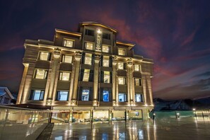 A modern hotel with a prominent entrance, large windows, and a well-lit facade. - ARCO Hotels & Resorts Srinagar (Budgam)