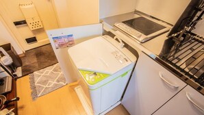 Une cuisine compacte équipée d’un lave-linge, d’un four à micro-ondes et d’une cuisinière.