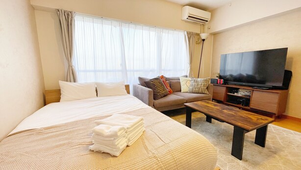 Une chambre d’hôtel avec un lit, un canapé, une télévision et une table basse.