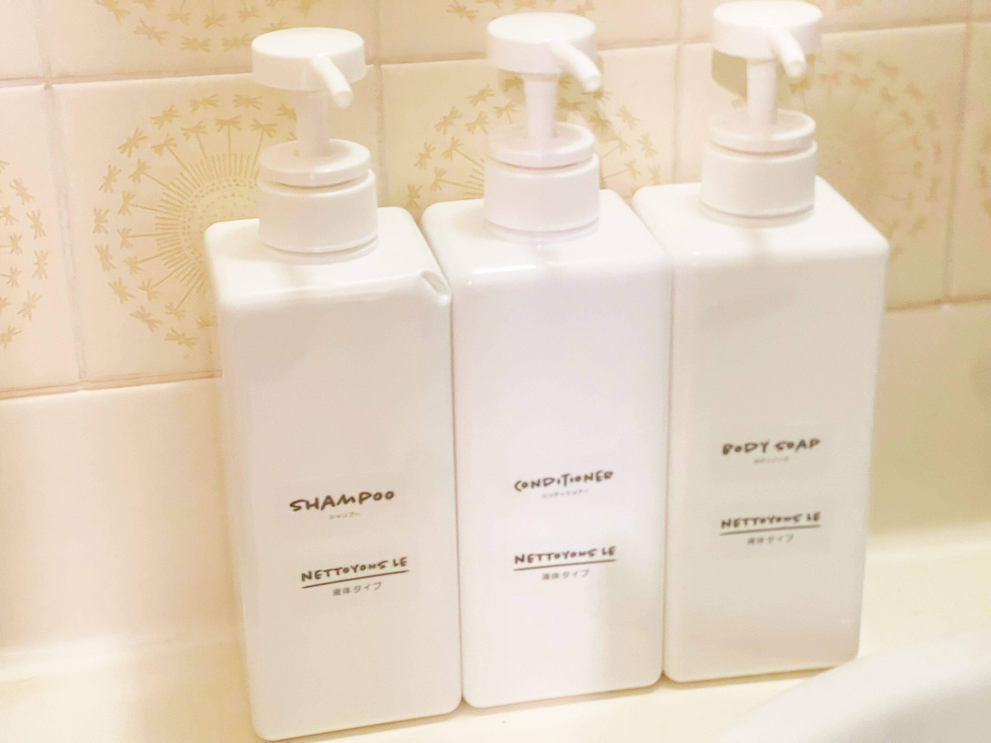 Trois bouteilles de shampoing et d’après-shampoing sur le comptoir d’une salle de bain.