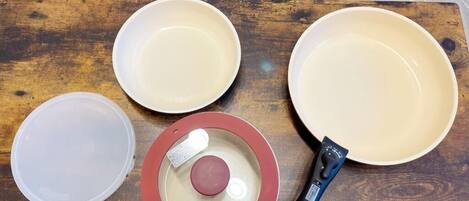 A wooden table with four bowls, a lid, and a pepper grinder.