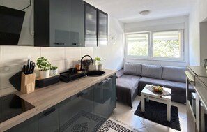 Uma cozinha moderna com forno embutido, pia e bancada com plantas em vasos.