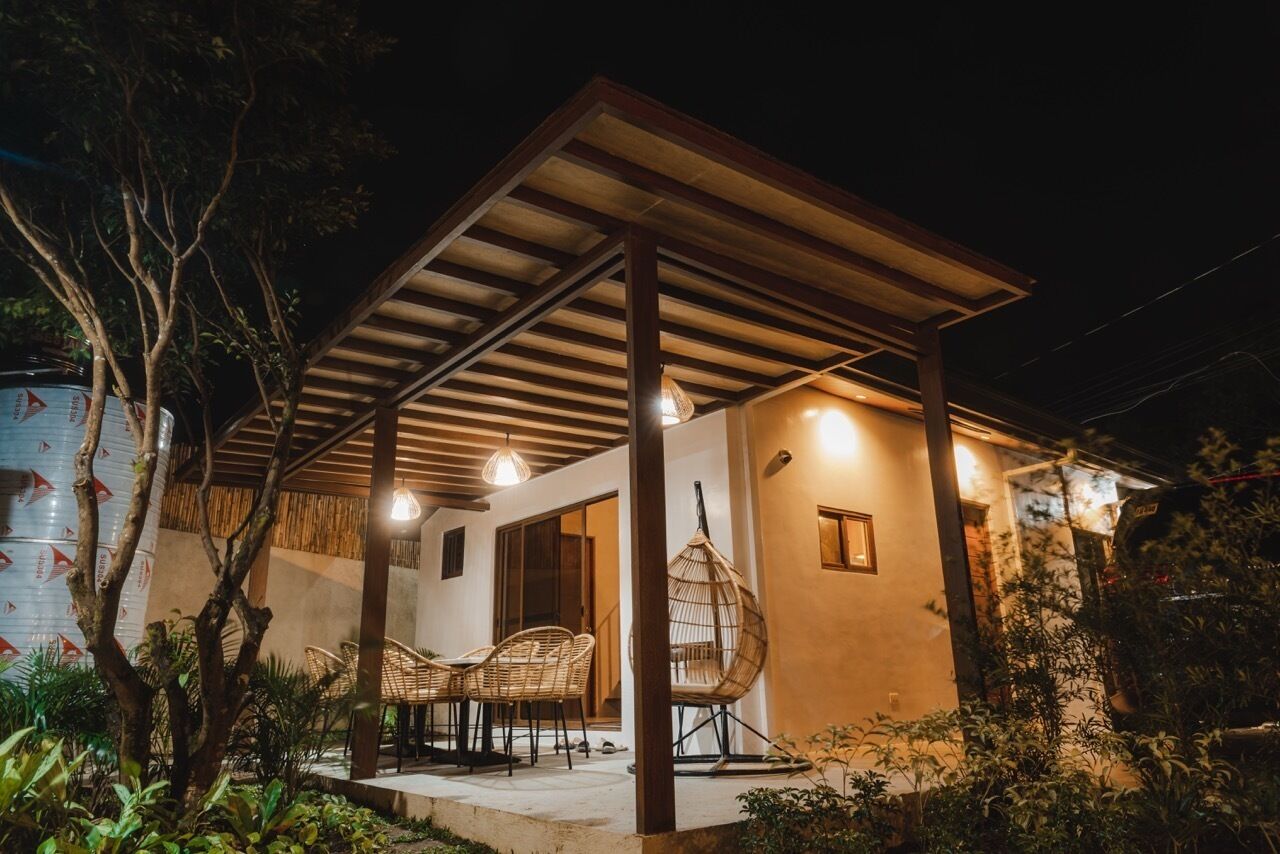 A covered outdoor area with a wooden pergola, hanging chairs, and a table.