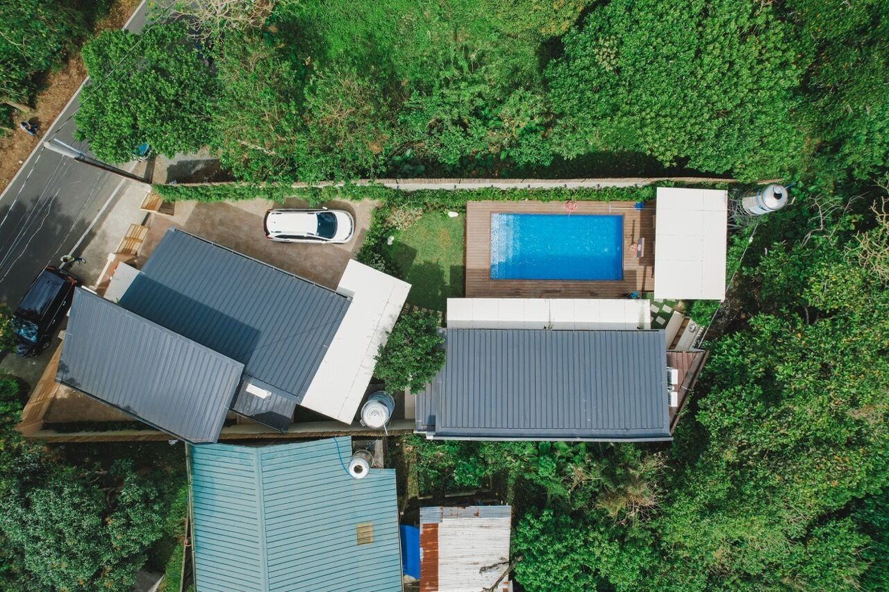 Vue aérienne d’une propriété résidentielle dotée d’une piscine, d’un garage et d’une grande maison avec un toit en pente.