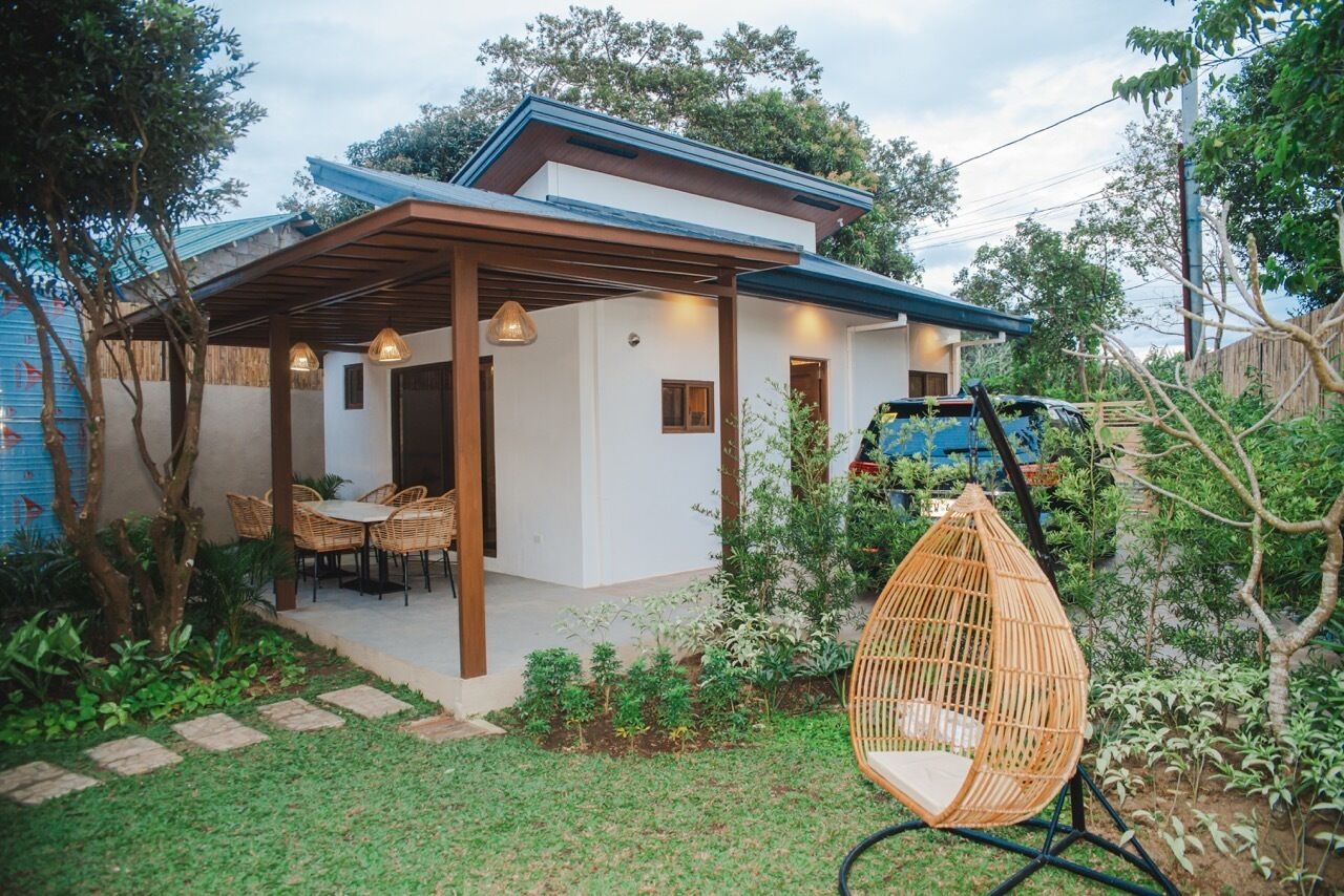 Une maison moderne dotée d’un patio couvert, d’un espace salon extérieur et d’un fauteuil suspendu.