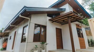 Een modern huis met twee verdiepingen, een plat dak, grote ramen en een houten deur.