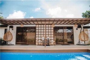 Un espace piscine extérieur moderne, doté d’une pergola, de sièges et offrant une vue sur la piscine.