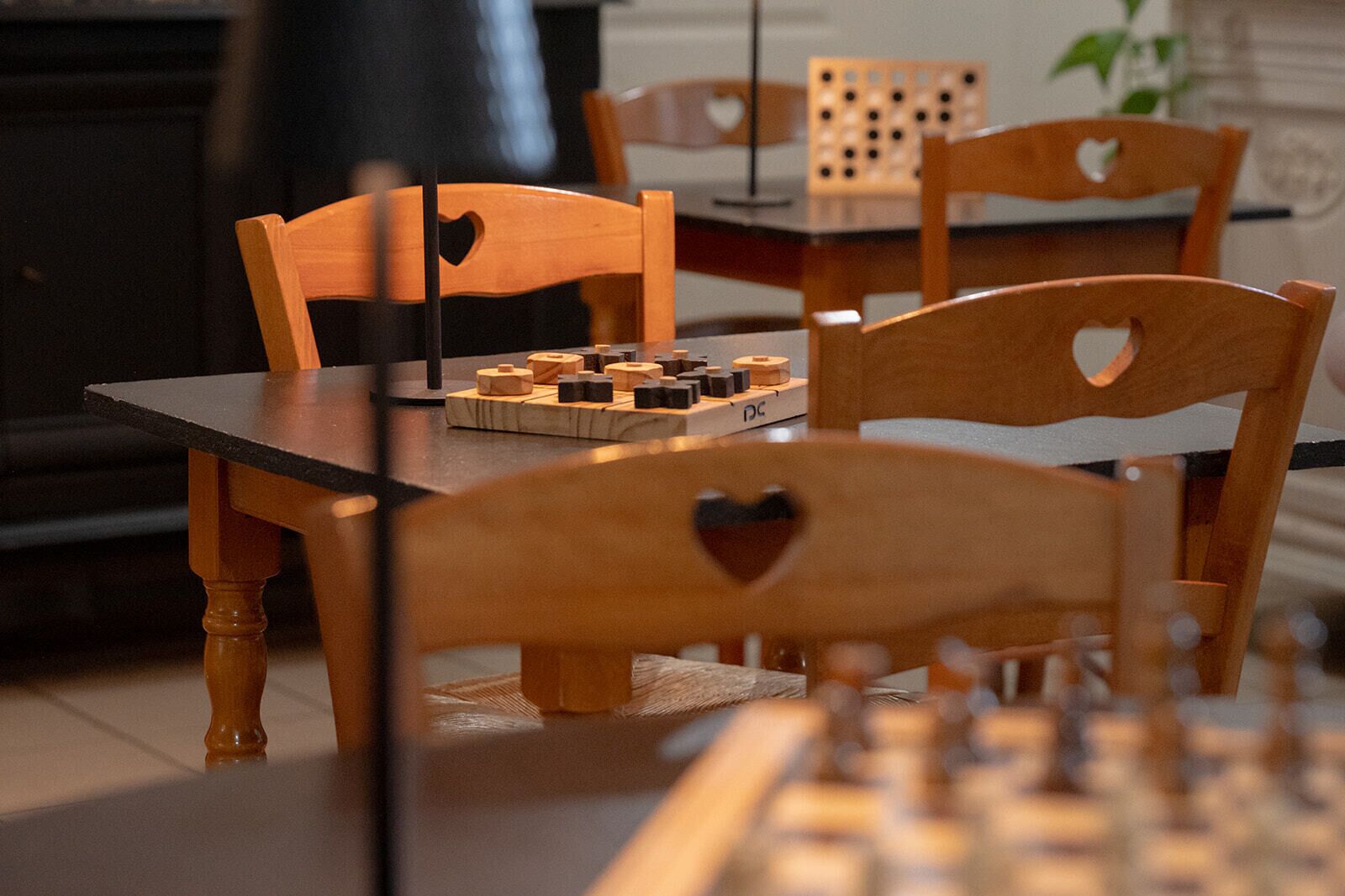 Une table à manger avec un jeu d’échecs et des chaises en bois ornées de découpes en forme de cœur.