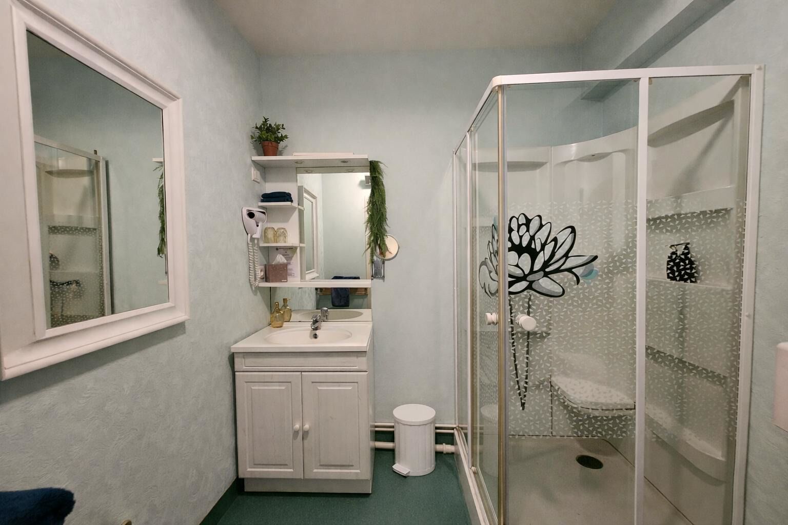 A bathroom with a white vanity, a glass shower enclosure, and a mirror above the sink.