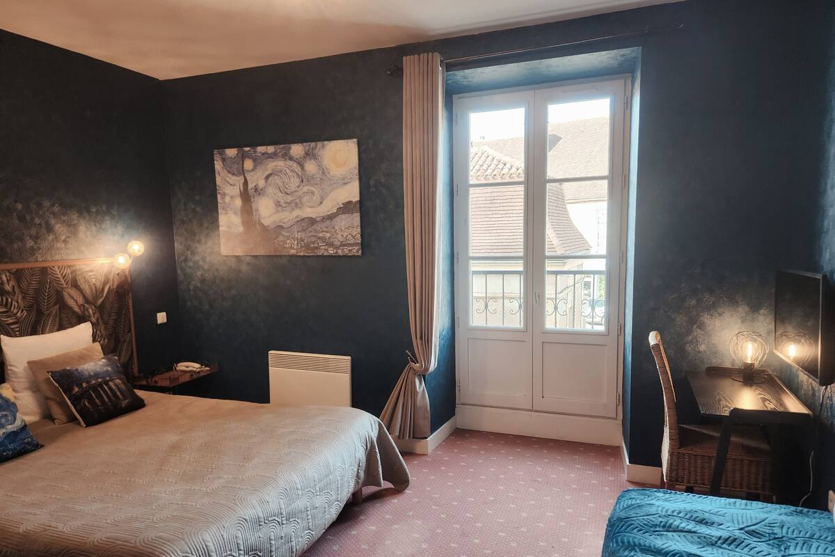 A bedroom with a bed, a desk, a chair, a window, and a painting on the wall.