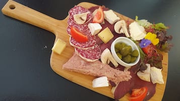 Una tabla de madera con diversos quesos, embutidos y verduras.