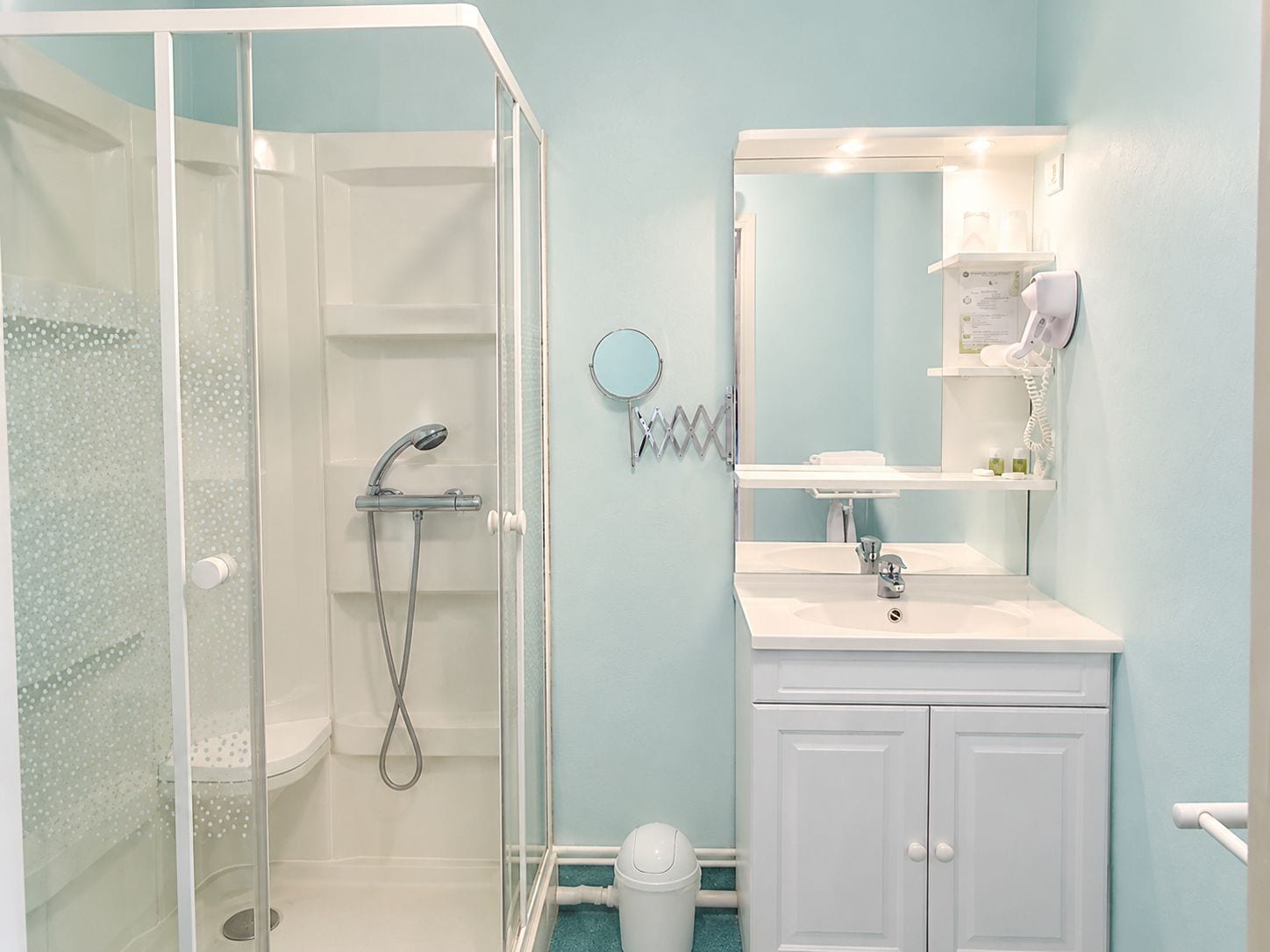 Un baño con ducha de vidrio, lavamanos con espejo y inodoro.
