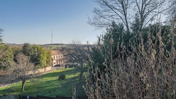 Zona residencial con una casa, césped y un árbol con vainas colgantes.