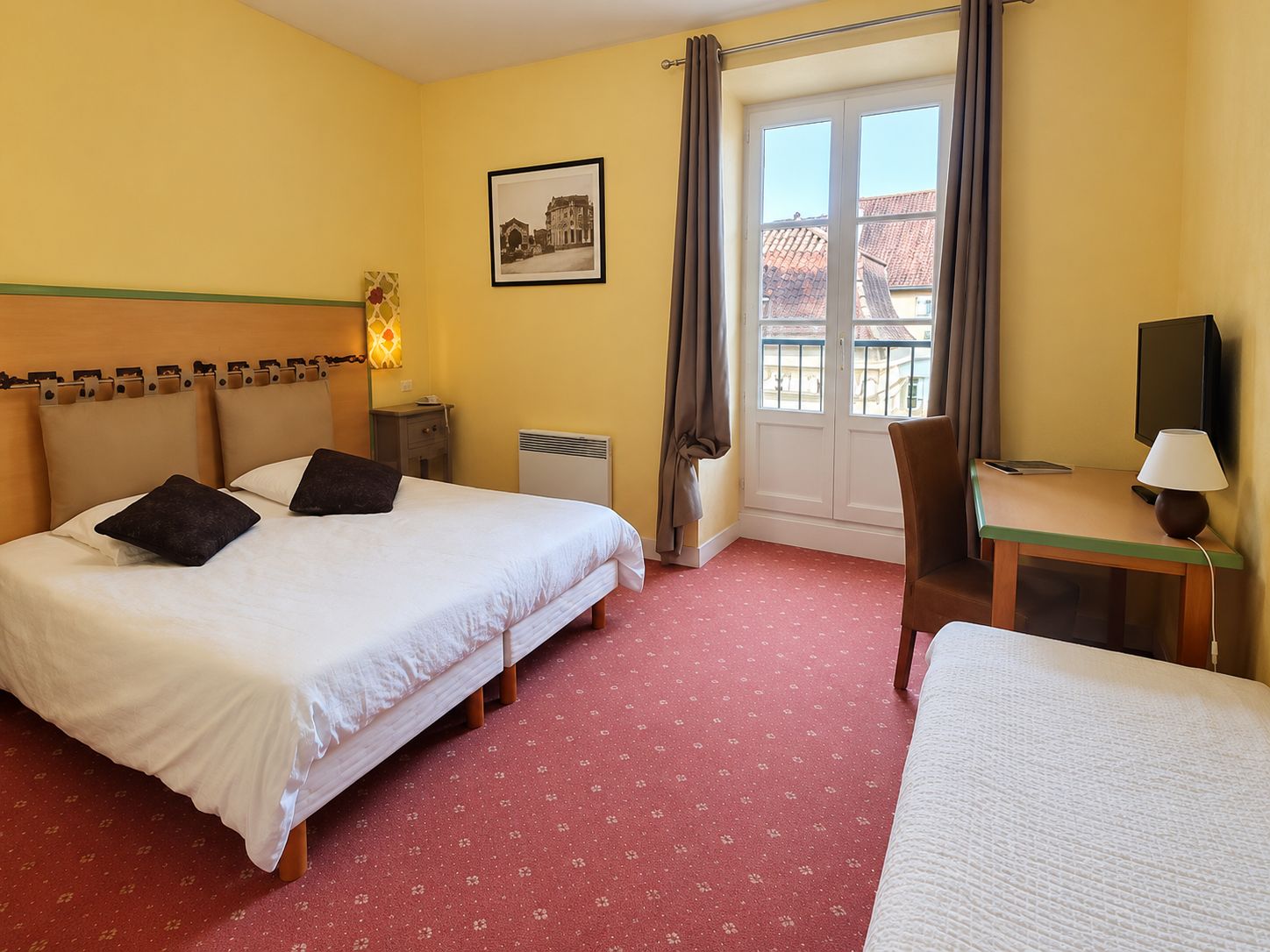 Une chambre d’hôtel avec deux lits, un bureau, une chaise, une télévision et une fenêtre avec des rideaux.