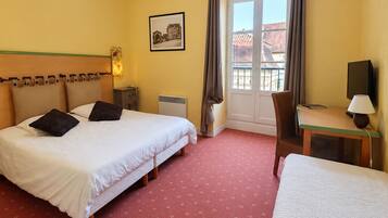 Une chambre d’hôtel avec deux lits, un bureau, une chaise, une télévision et une fenêtre avec des rideaux.