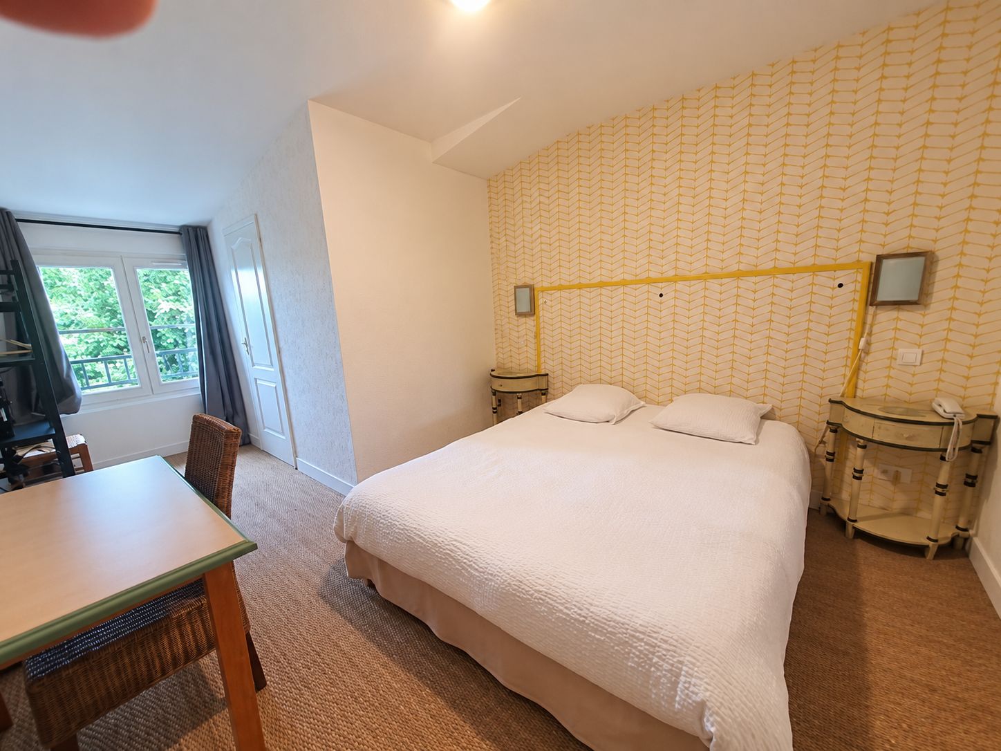 Une chambre à coucher avec un lit, des tables de chevet, un bureau et une chaise.