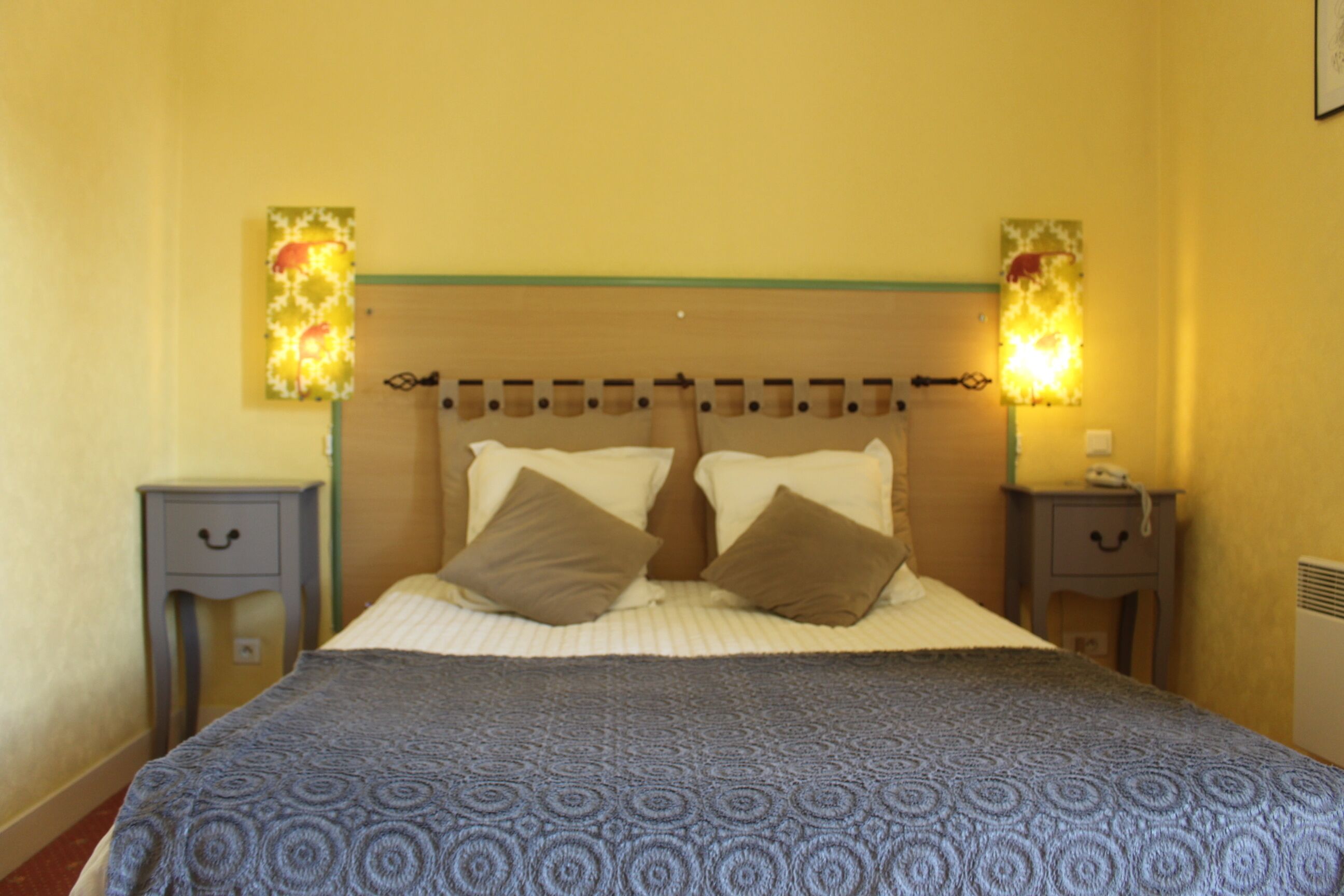 Un dormitorio con una cama, dos mesitas de noche y lámparas de pared.