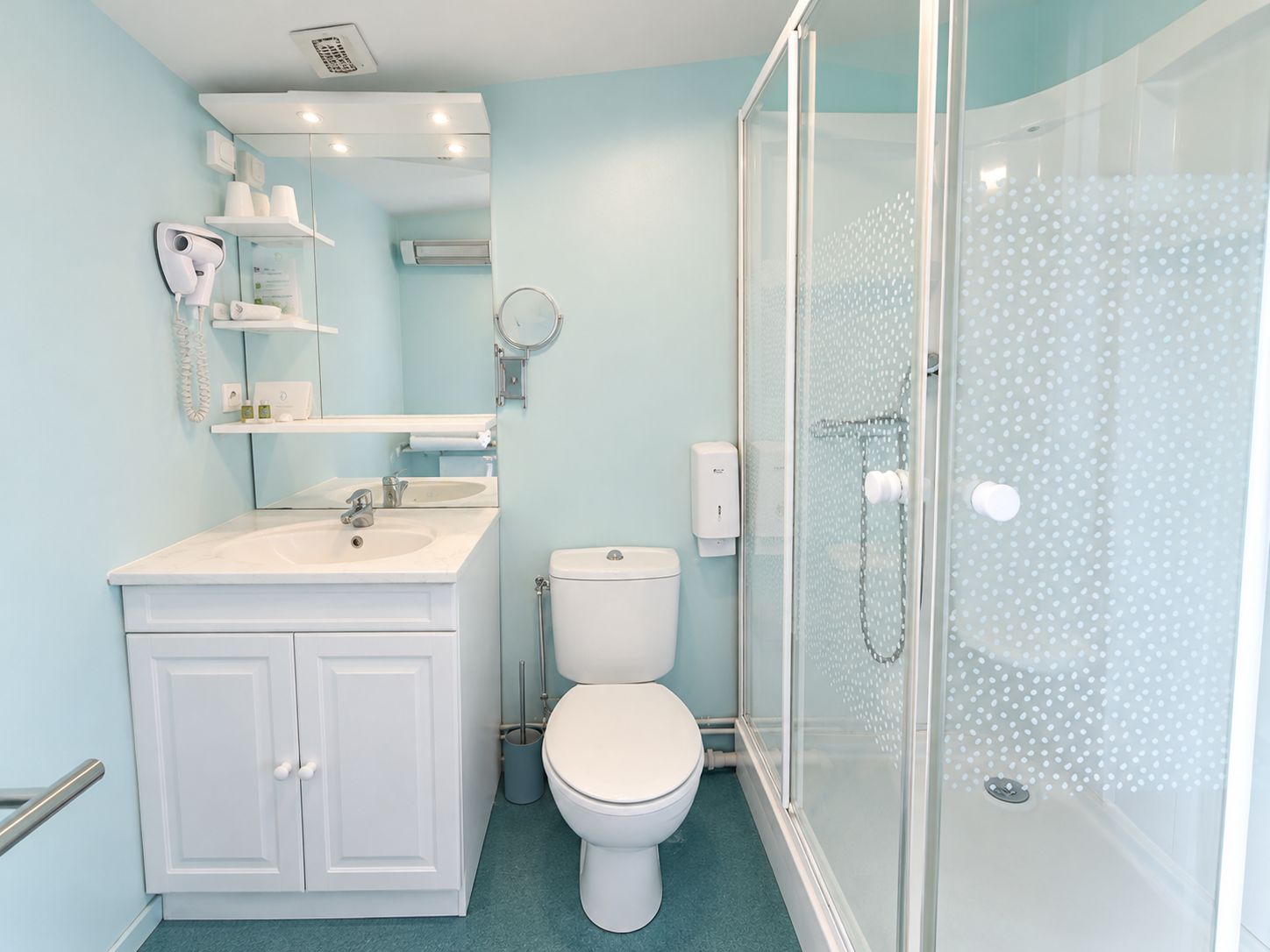 Une salle de bain avec un lavabo blanc, des toilettes et une douche fermée par une paroi de verre.