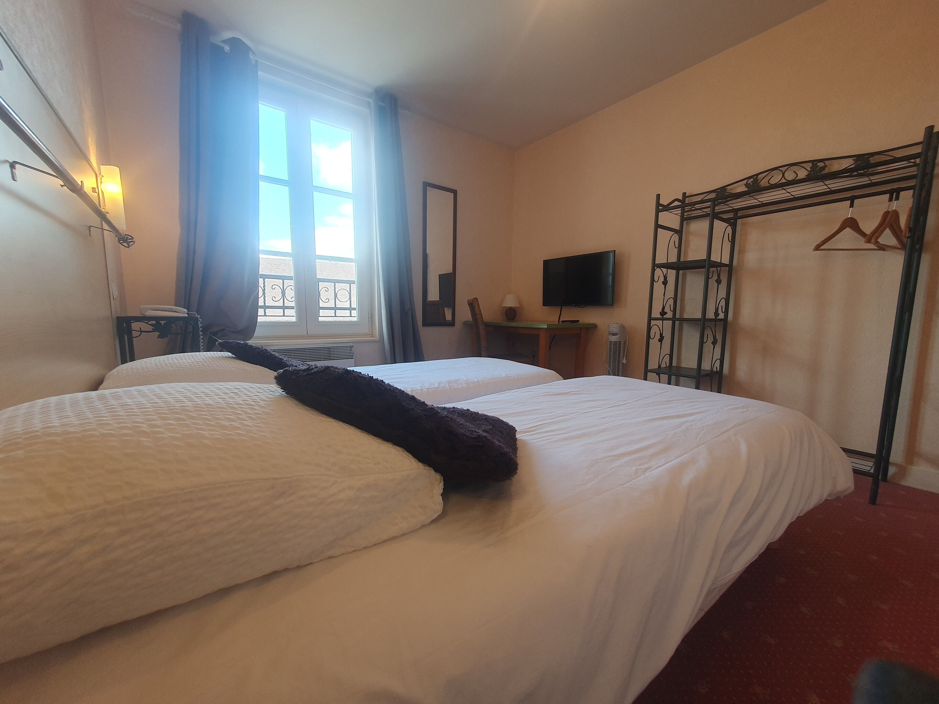 A hotel room with two beds, a TV, a desk, and a wardrobe.