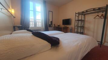 A hotel room with two beds, a TV, a desk, and a wardrobe.
