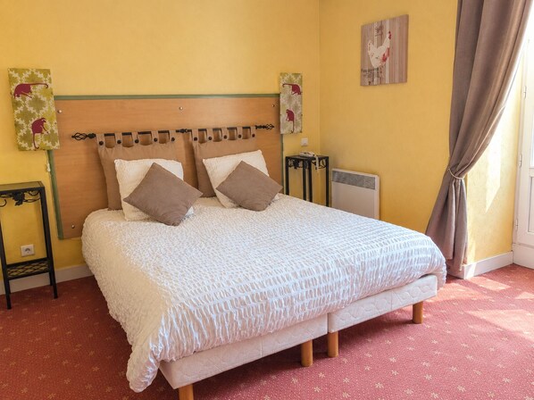 A bed with a headboard, two pillows, a bedside table with a lamp, and a radiator on the wall. - Hôtel Auberge du Fin Chapon - Dordogne (Excideuil)
